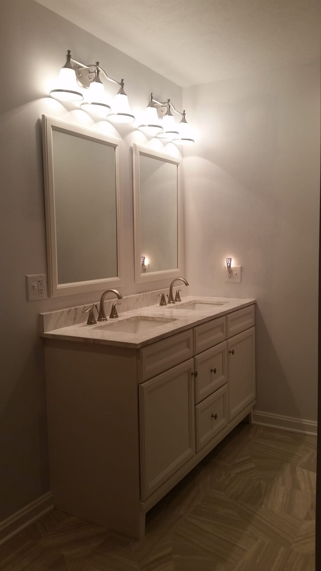 Bathroom double vanity with white cabinets, twin framed mirrors, and paired vanity light bars