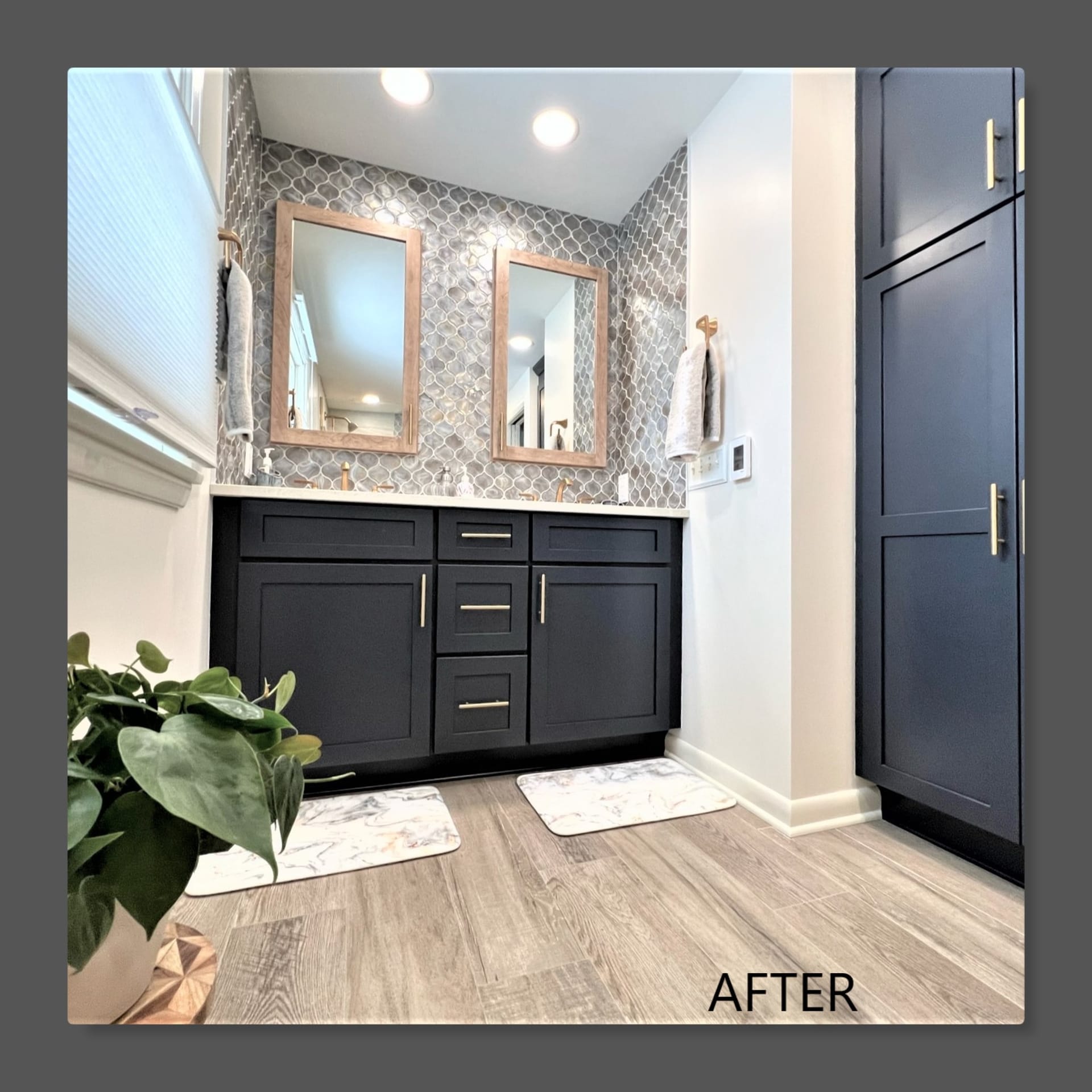 Bathroom double vanity with navy shaker cabinets, brass pulls, silver mosaic accent wall, wood-look plank flooring, Erie PA