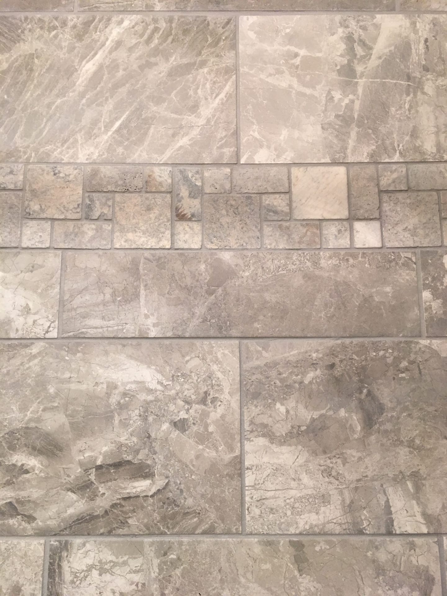 Grey marble-look tile wall with a vertical natural stone mosaic accent inset