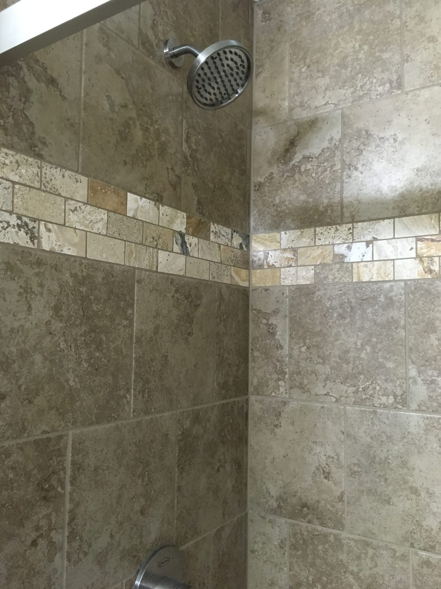 Tile shower with travertine walls, natural stone mosaic vertical accent strip, and brushed-nickel showerhead