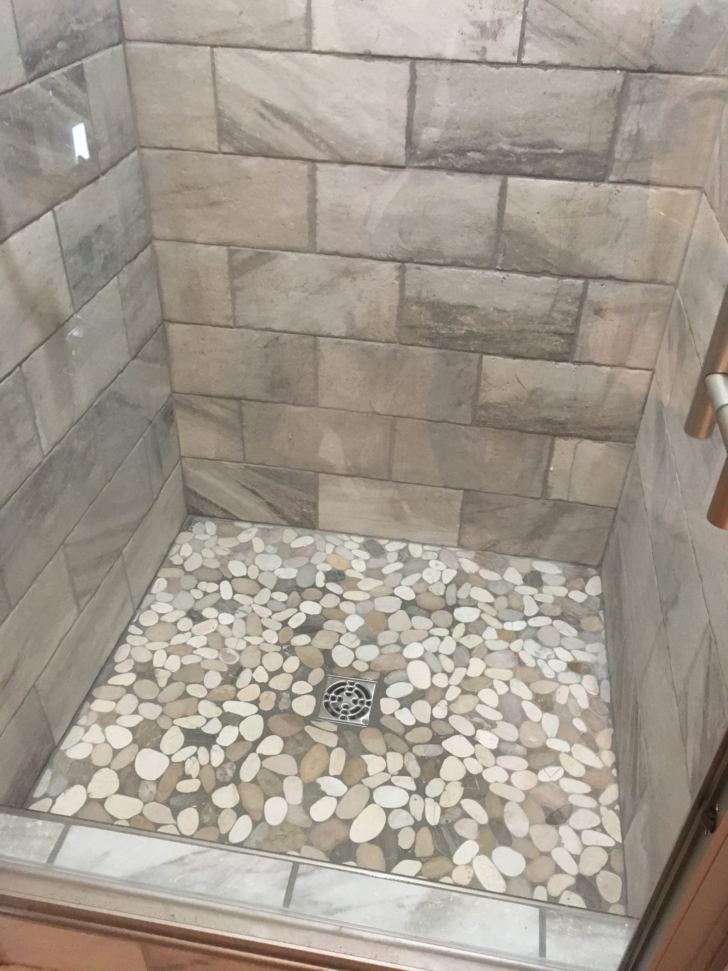 Tile shower with grey marble-look walls and a cream sliced-pebble mosaic shower floor