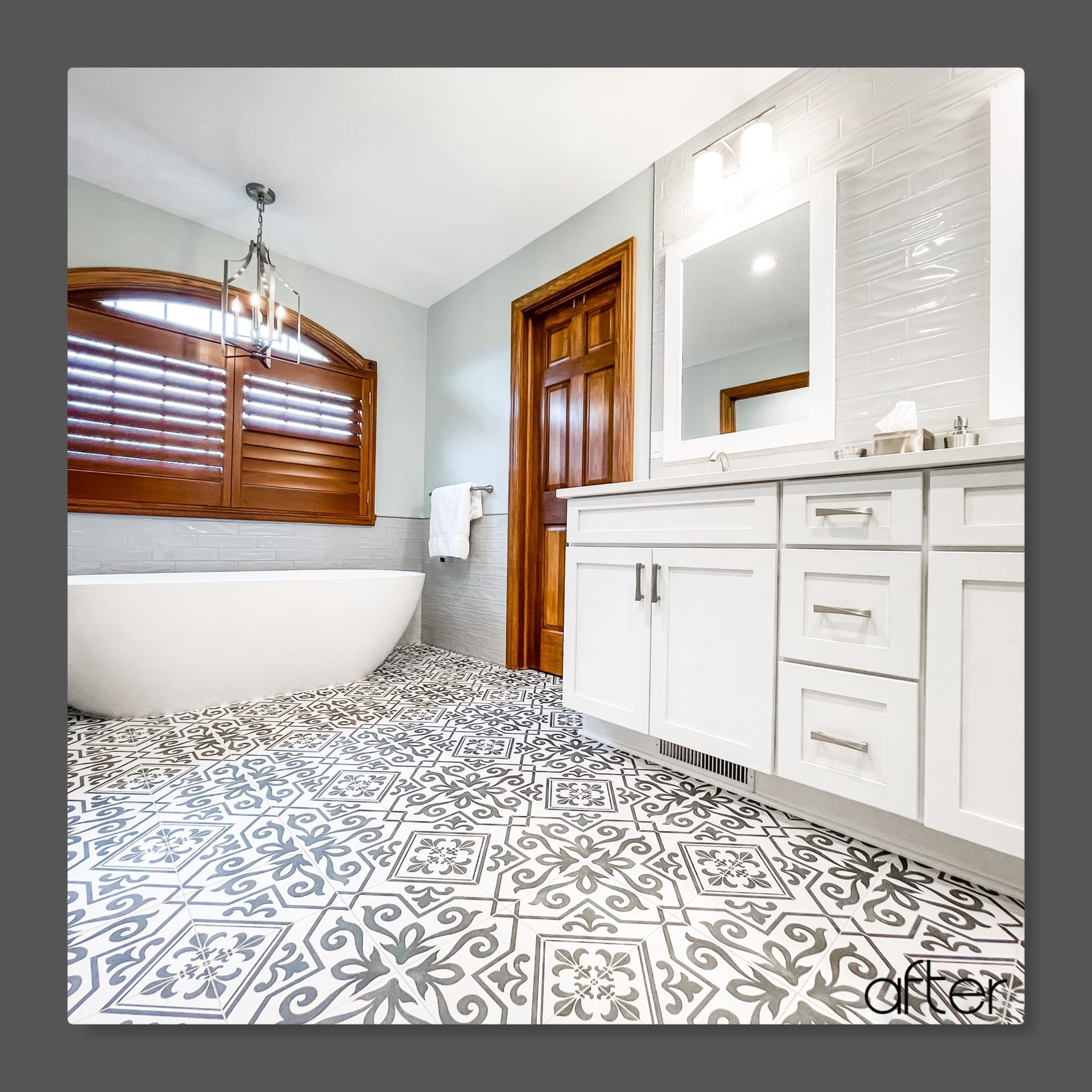 Bathroom with freestanding soaking tub, black-and-white patterned cement tile floor, white shaker vanity, wood shutters, Erie County