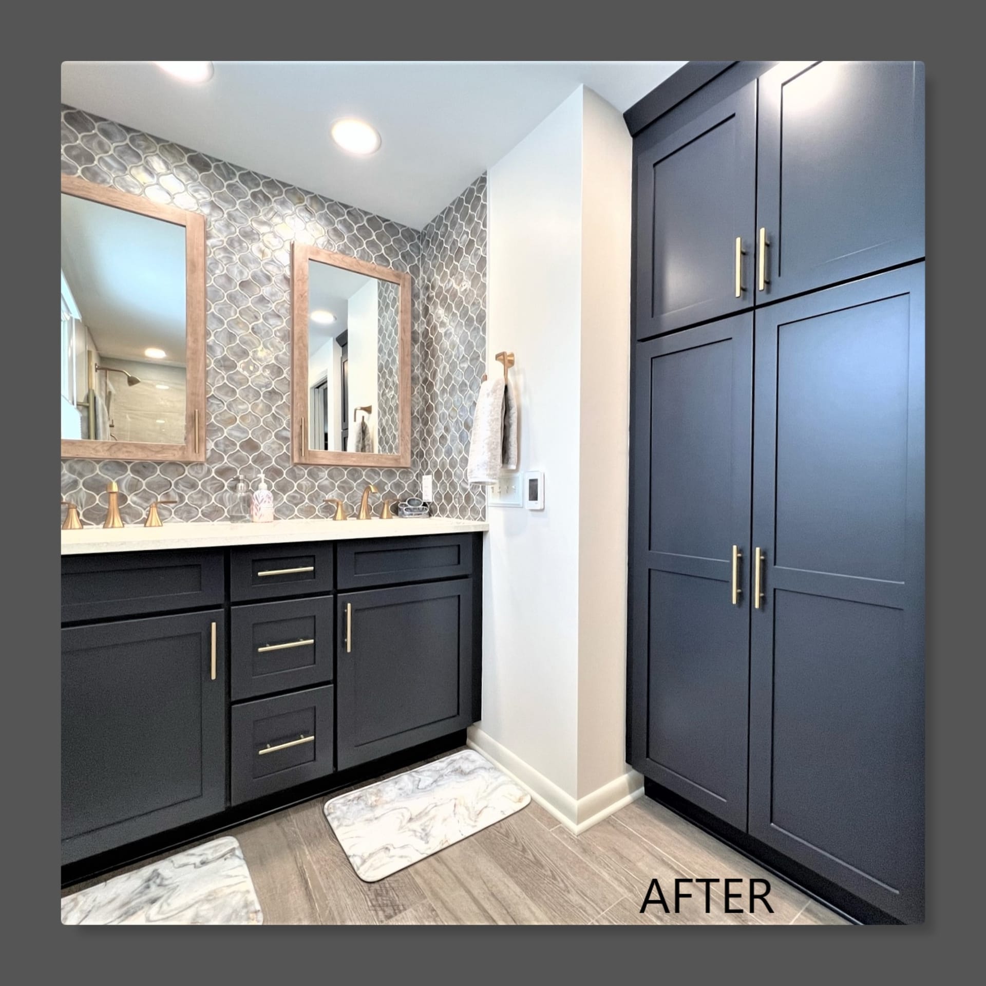 Bathroom double vanity with navy shaker cabinets, brass pulls, silver arabesque mosaic accent wall, and linen tower