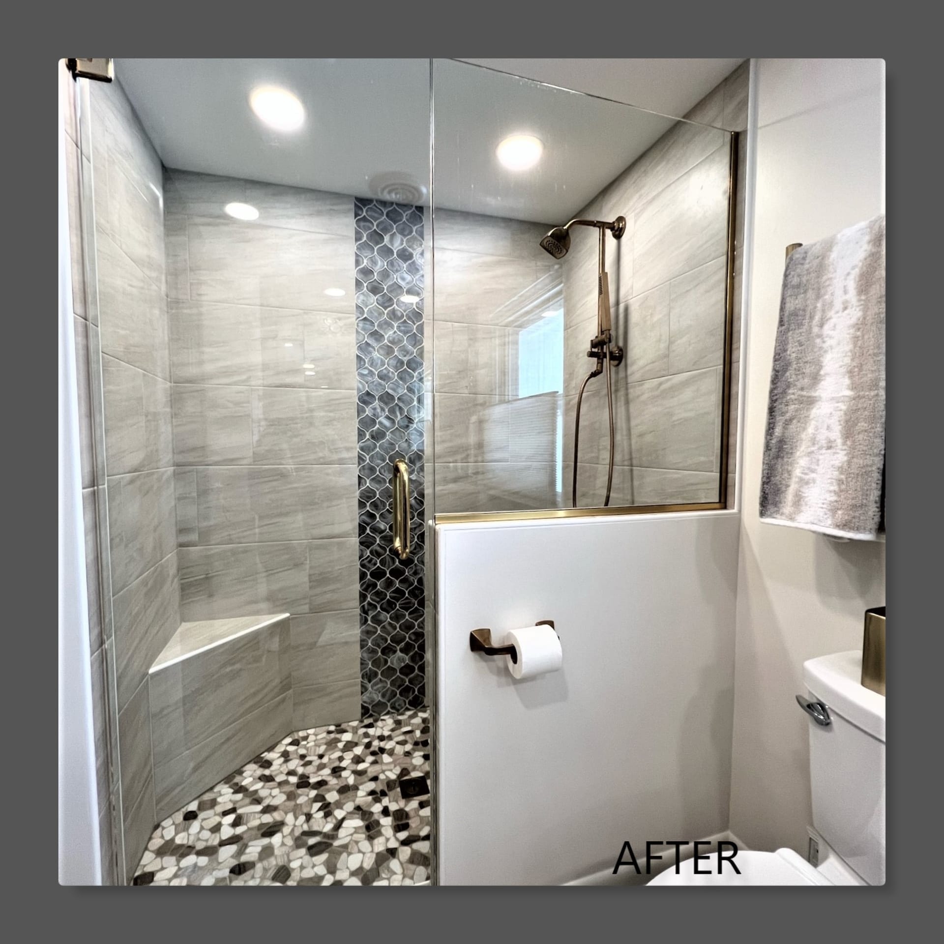 Corner glass tile shower with grey wood-look tile, hex mosaic accent strip, tile bench, and pebble mosaic floor