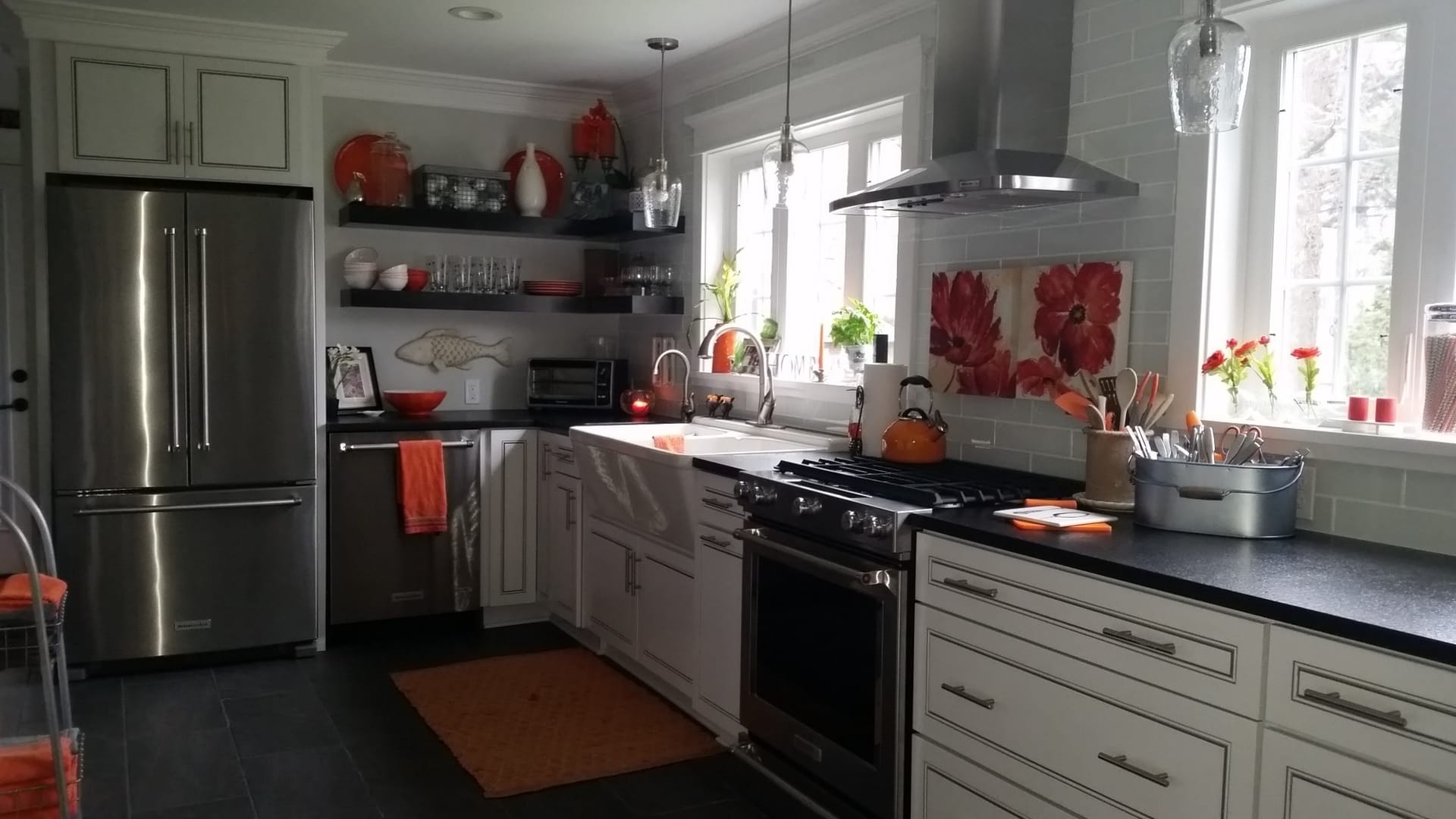 White shaker kitchen with stainless chimney hood, open grey shelving, white subway tile, black counters, farmhouse sink, Edinboro