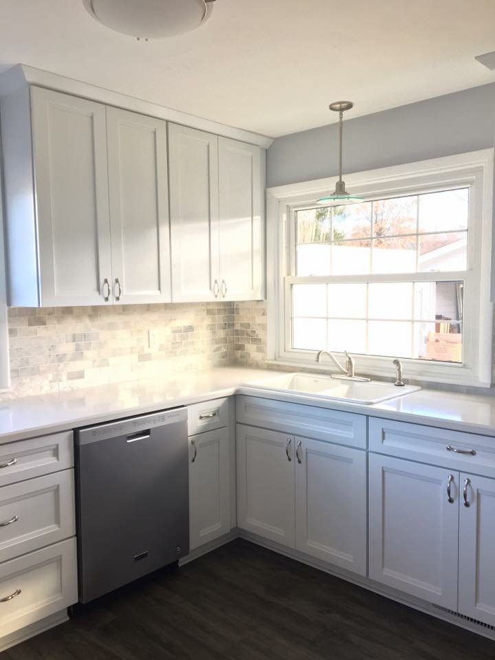 White shaker kitchen with marble-look subway tile, white quartz counters, stainless dishwasher, and dark plank flooring, Erie PA
