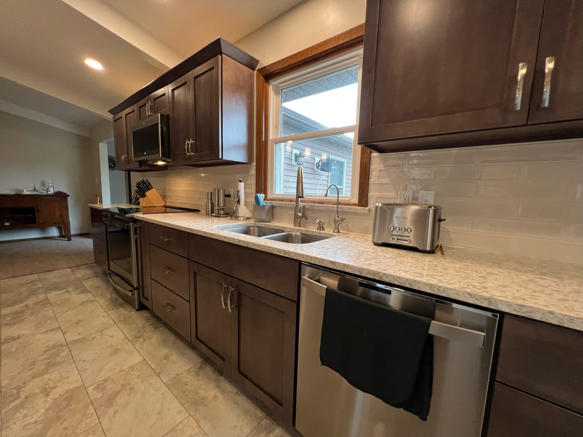 Espresso shaker kitchen with white subway tile, speckled granite counters, stainless dishwasher, and tile flooring