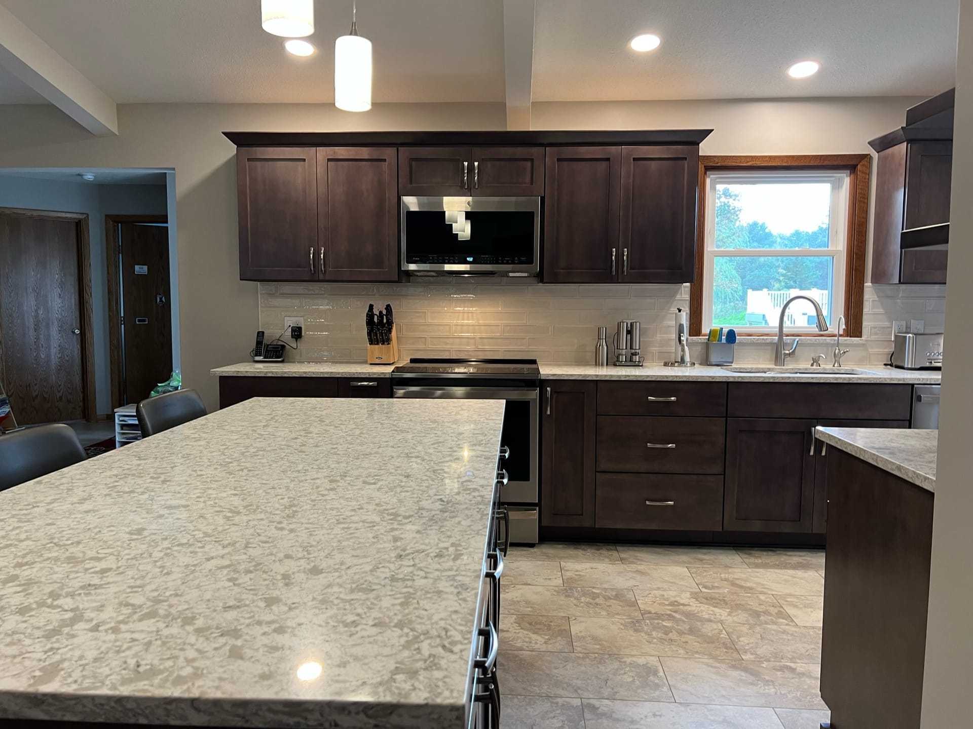 Dark shaker kitchen with white subway tile, speckled granite island, stainless appliances, and tile flooring, Erie PA