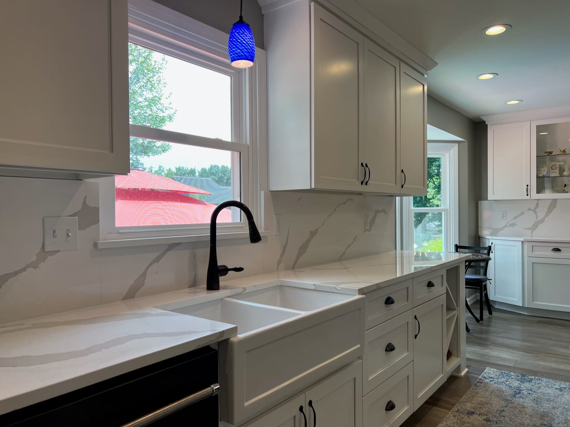 White shaker kitchen with marble-look quartz counters, full-height slab backsplash, farmhouse apron sink, and matte-black faucet, Edinboro