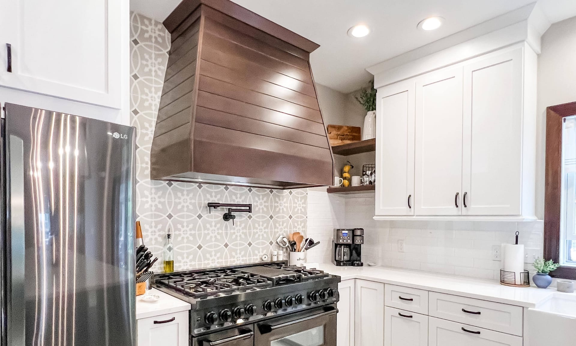 White shaker kitchen with wood range hood, grey patterned cement-tile backsplash, white quartz counters, and open shelving