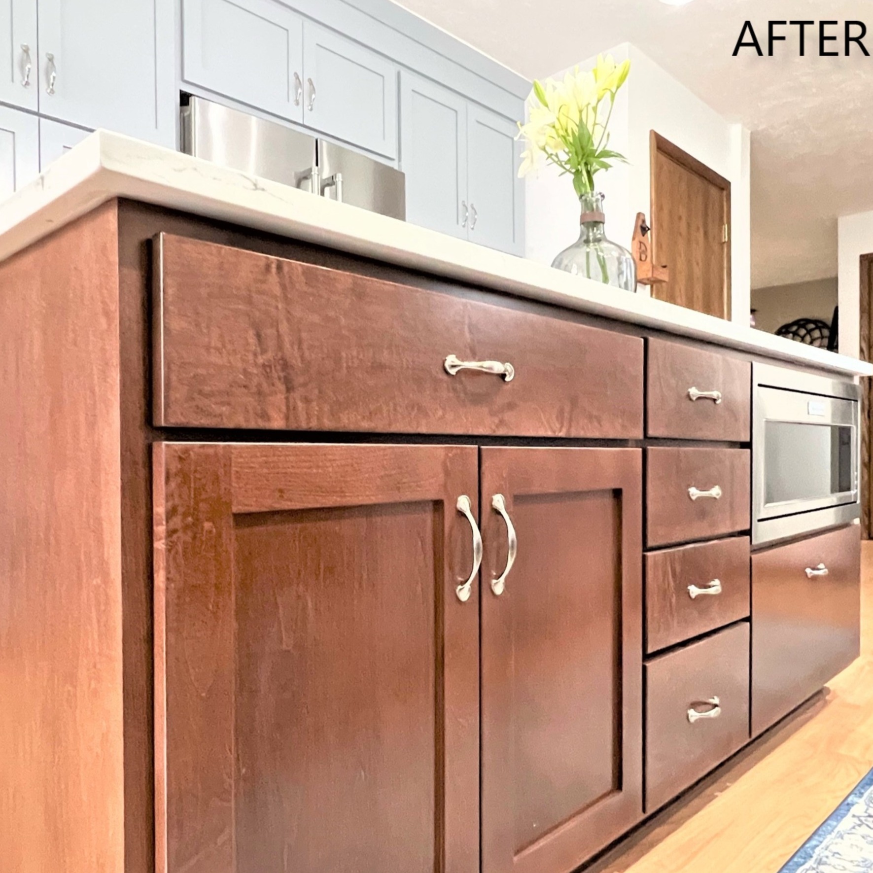Dark reddish-brown stained island with white quartz top, light blue perimeter cabinets, and microwave drawer, Edinboro