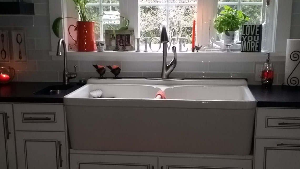 White double-bowl farmhouse sink with dark counters, white subway tile, and gooseneck faucet, cream cabinetry, Erie County