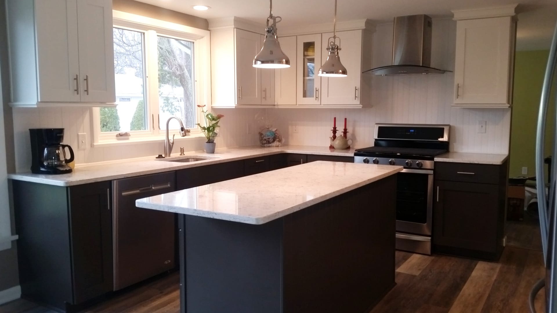 Two-tone kitchen with white uppers, espresso lowers, stainless chimney hood, white quartz island, plank flooring, Erie PA