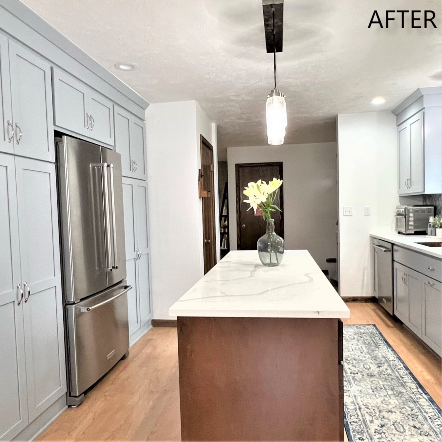 Grey kitchen with floor-to-ceiling cabinets, wood-base island, marble-look quartz top, and stainless french-door refrigerator
