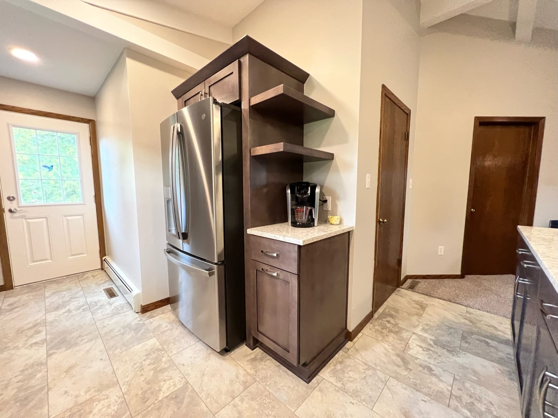 Espresso wood kitchen with coffee-station nook, floating shelves, stone counter, and stainless french-door refrigerator, Edinboro