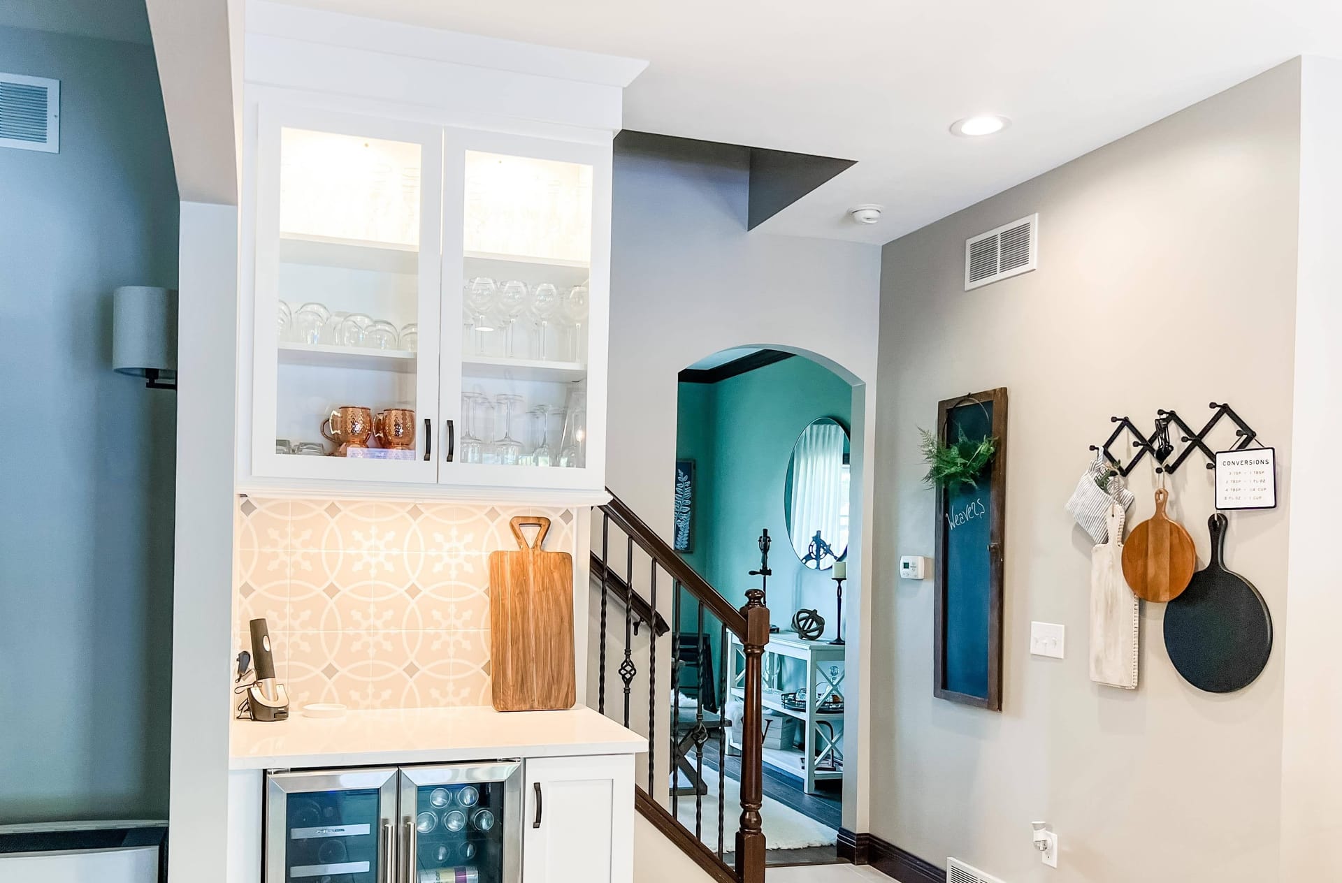 White beverage station with glass-front cabinet, patterned cement tile backsplash, and built-in beverage fridge