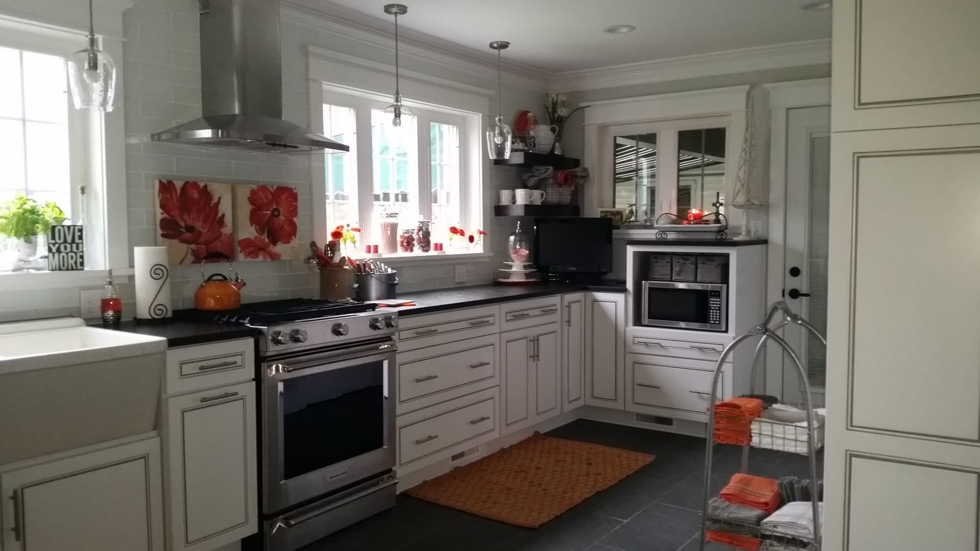 Cream glazed shaker kitchen with stainless chimney hood, dark counters, farmhouse apron sink, and dark tile flooring, Edinboro