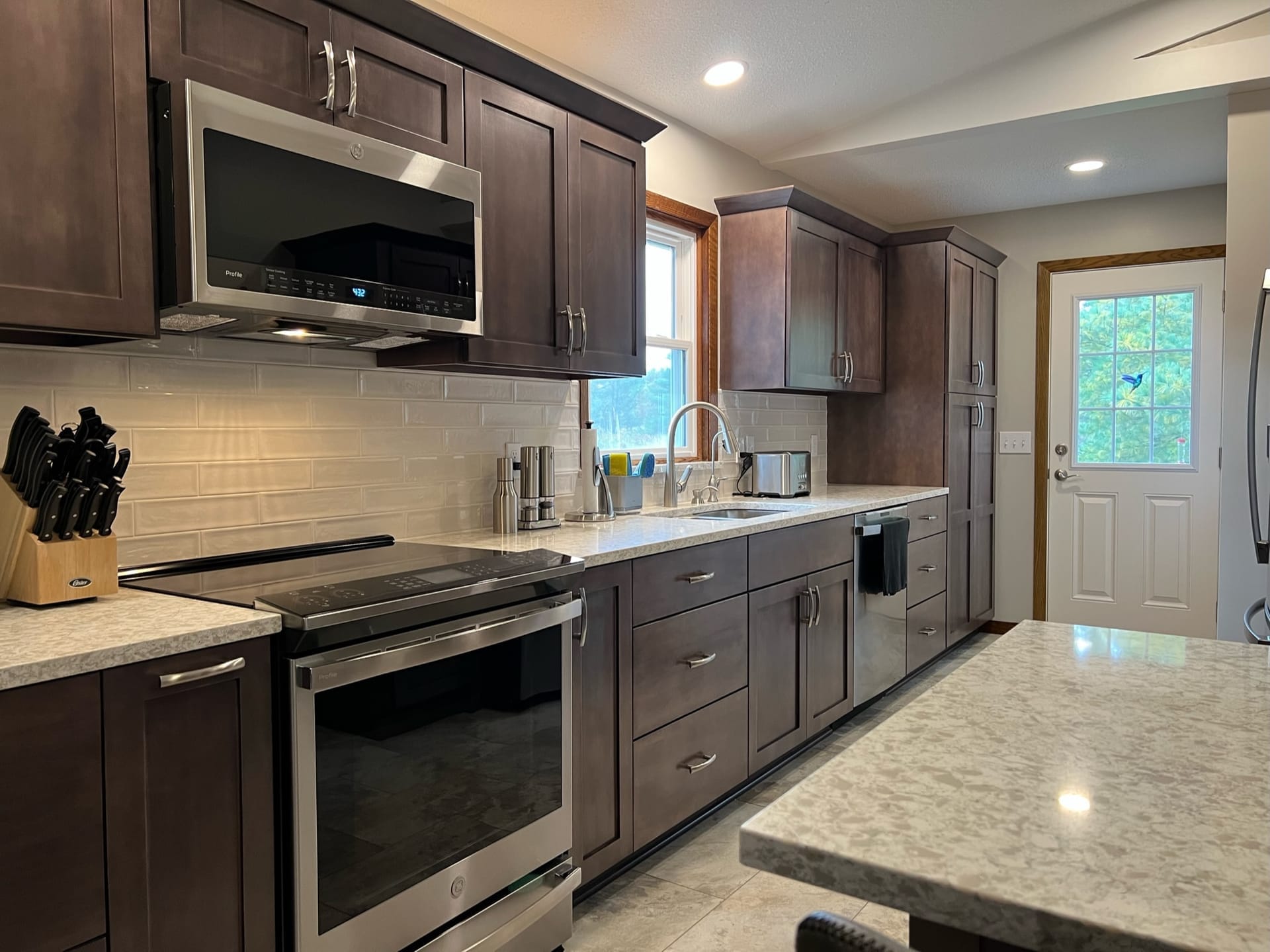 Espresso shaker kitchen with white subway tile, speckled granite island, stainless appliances, and tile flooring, Erie County