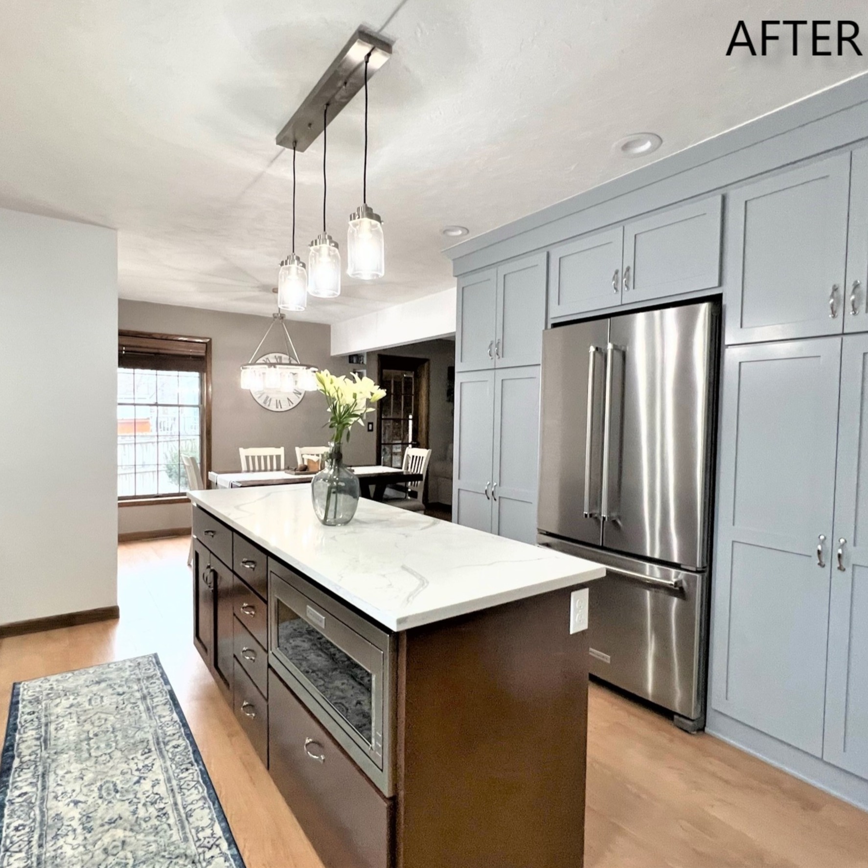 Two-tone kitchen with light blue perimeter cabinets, dark stained island, white quartz counters, and mason-jar pendant lights